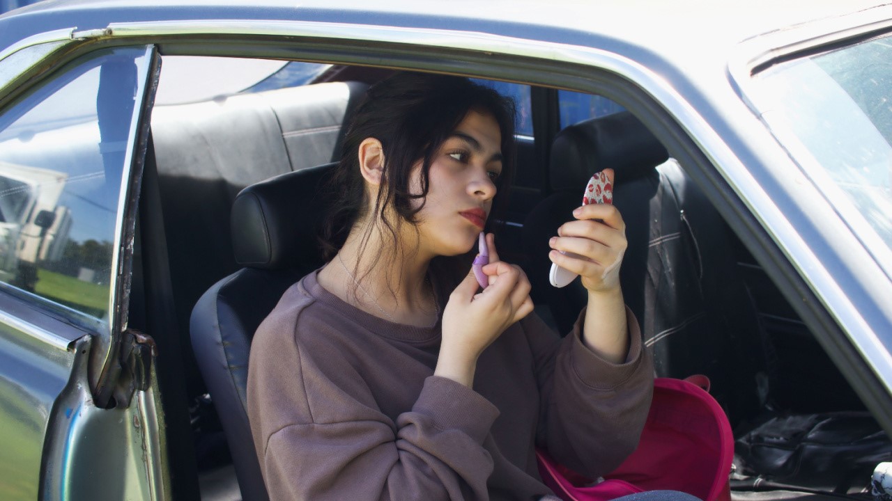 Girl makes up her face inside a car with cosmetics