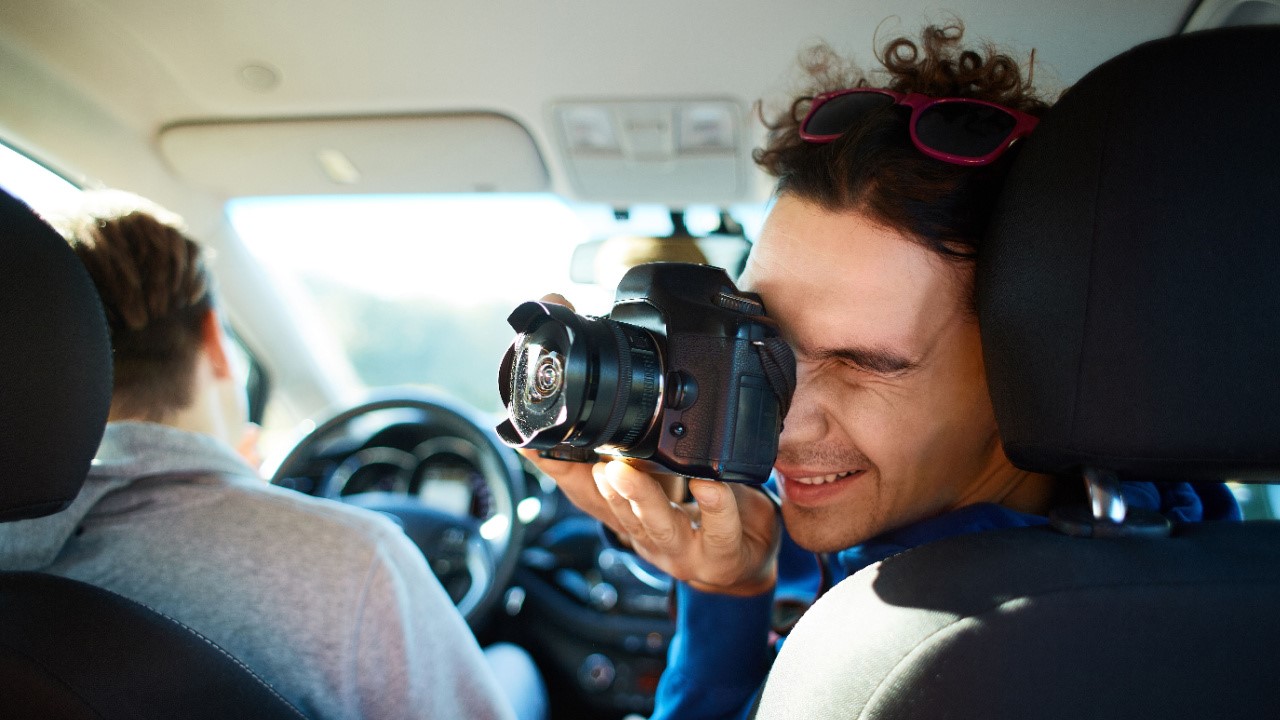 Young man photographer taking photo with camera inside the car cabin