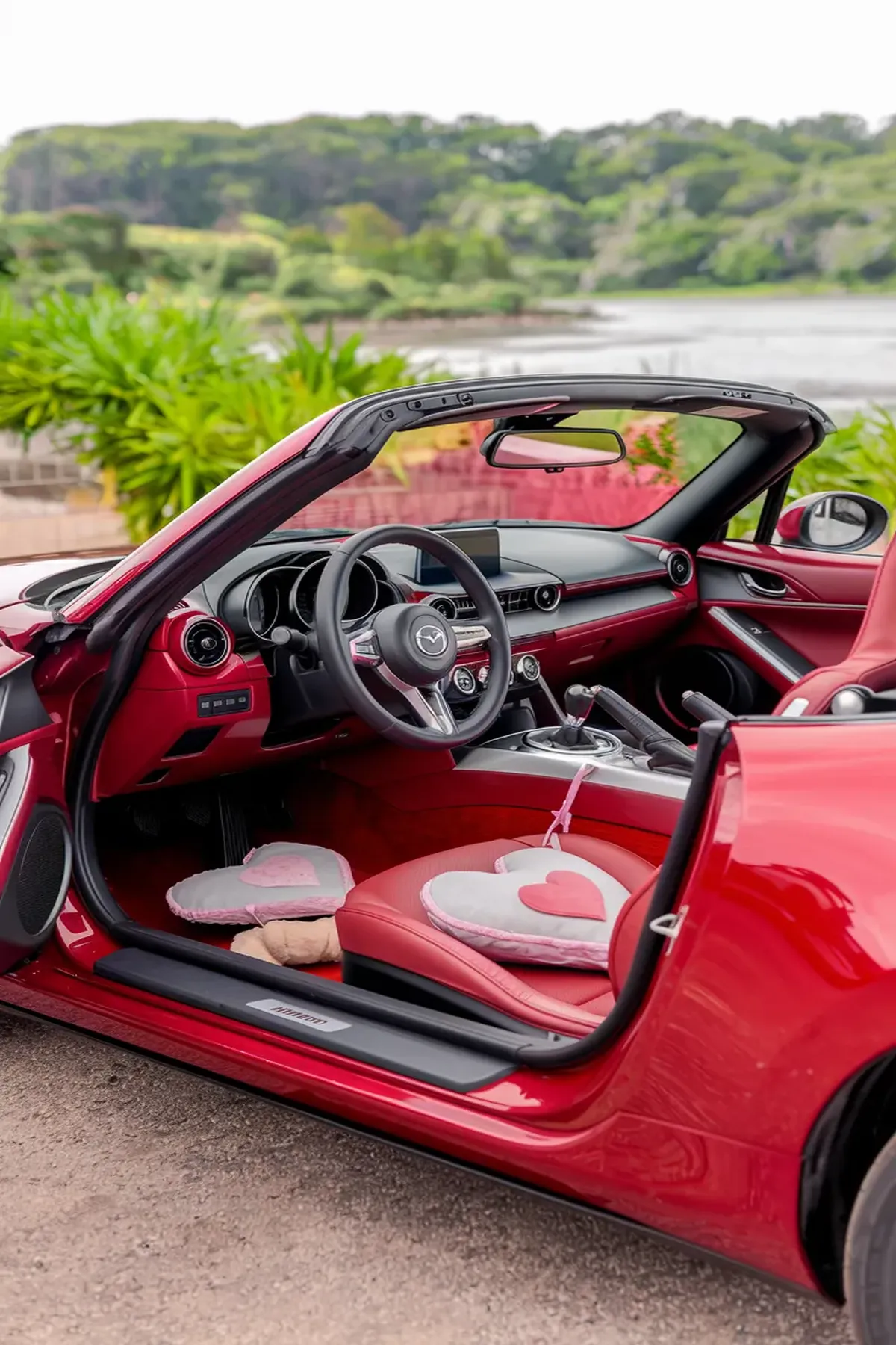 A red Mazda MX-5 Miata convertible parked by a coastal highway at sunset. 